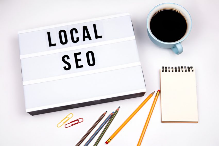 'local SEO' sign next to a cup of coffee, notepad, pencils, and paper clips